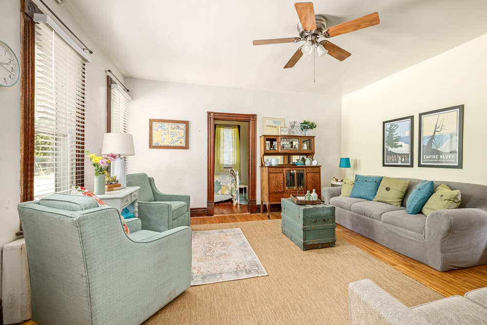 Bright and inviting living room with comfortable seating, decorative artwork, and a view into an adjoining room.